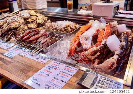 Fresh king crab legs shrimp skewers oysters and scallops are displayed on crushed ice Fresh king crab legs shrimp skewers oysters and scallops are displayed on crushed ice 124205431