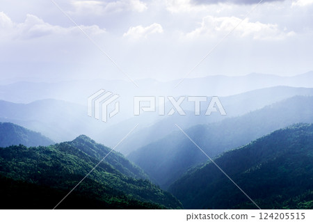 Picturesque blue mountain ranges glowing by sun rays Picturesque blue mountain ranges glowing by sun rays 124205515