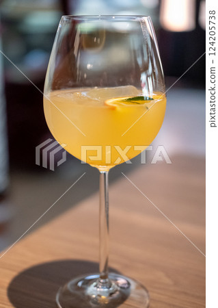 A glass of citrus sangria, featuring a vibrant orange hue with ice and a slice of fruit garnish 124205738