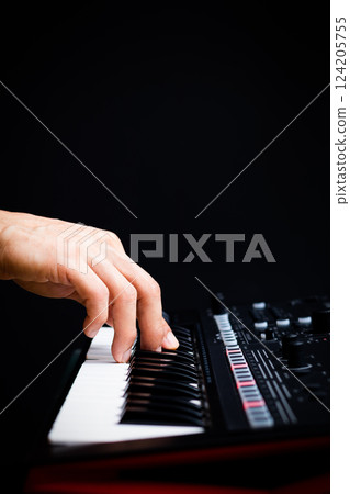 male hand playing on music synthesizer keyboard keys on black. music background male hand playing on music synthesizer keyboard keys on black. music background 124205755
