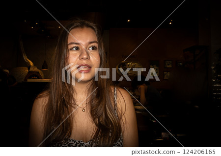 A portrait of a sweet teenage Asian girl. Black background. 124206165