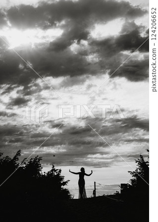 Silhouette of Woman Reaching Out Under Dramatic Sky 124206652