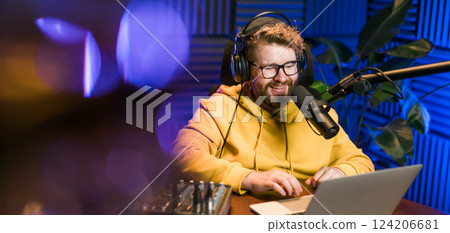 Young smiling male radio presenter banner talking into the microphone and reading news, information and communication concept. Podcast and internet streaming concept. Young smiling male radio presenter banner talking into the microphone and reading news, information and communication concept. Podcast and internet streaming concept. 124206681