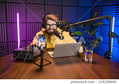 Young smiling male radio presenter talking into the microphone and reading news, information and communication concept. Podcast and internet streaming concept. 124206690