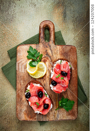 sandwiches with cream cheese, chum salmon, cold smoked, grain bread, on a cutting board, top view, breakfast, lemon and parsley, no people, sandwiches with cream cheese, chum salmon, cold smoked, grain bread, on a cutting board, top view, breakfast, lemon and parsley, no people, 124207008