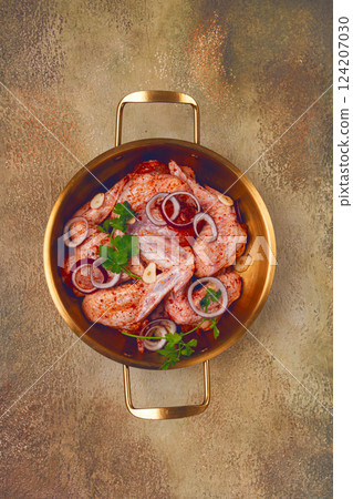 Chicken wings, in a brass saucepan, ready for cooking, grilling or baking, in a home kitchen, no people Chicken wings, in a brass saucepan, ready for cooking, grilling or baking, in a home kitchen, no people 124207030