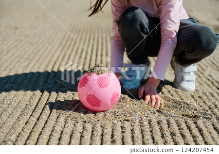 Young Child Playing on Sand Field with Pink Soccer Ball Young Child Playing on Sand Field with Pink Soccer Ball 124207454