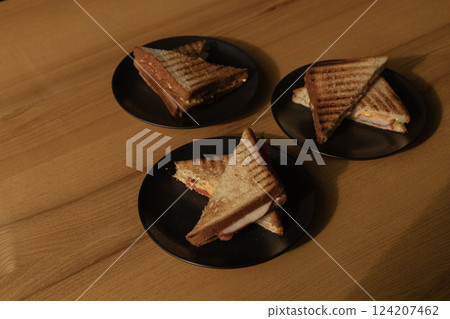 three hot sandwiches on plates on the table, lunch three hot sandwiches on plates on the table, lunch 124207462