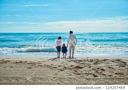 Family Enjoying a Stroll Along the Beach on a Sunny Day Family Enjoying a Stroll Along the Beach on a Sunny Day 124207469