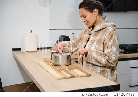 Young Woman Preparing Food in a Modern Cozy Home Kitchen Young Woman Preparing Food in a Modern Cozy Home Kitchen 124207488