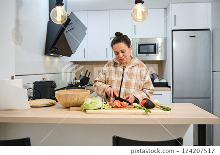 Woman Preparing Fresh Salad in Modern Home Kitchen Setting Woman Preparing Fresh Salad in Modern Home Kitchen Setting 124207517