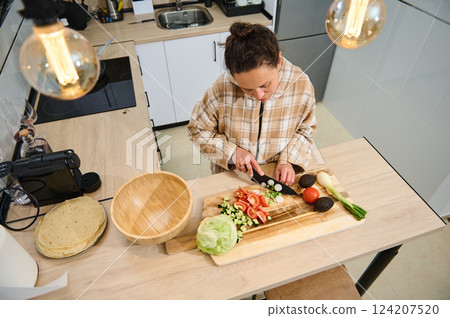 Woman Prepares Fresh Salad Ingredients in a Modern Kitchen Woman Prepares Fresh Salad Ingredients in a Modern Kitchen 124207520