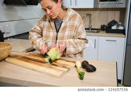 Woman Preparing Fresh Salad in a Cozy Home Kitchen Setting 124207536
