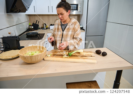 Young Woman Preparing Fresh Salad and Tortillas in a Cozy Home Kitchen 124207548