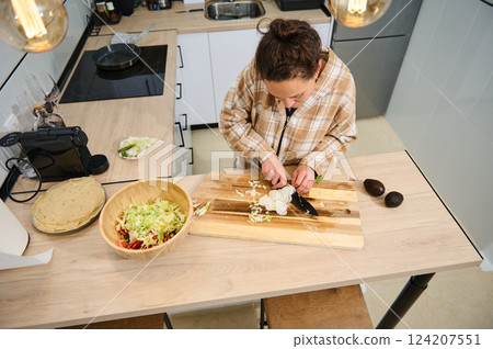 Woman Preparing Ingredients for a Healthy Salad in a Modern Kitchen 124207551