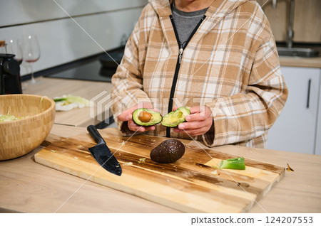 Person Preparing Fresh Avocado for a Healthy Meal in Modern Kitchen 124207553