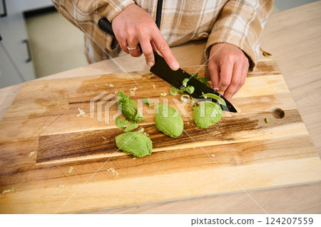 Person Slicing Avocado and Vegetables on Wooden Cutting Board for Cooking Person Slicing Avocado and Vegetables on Wooden Cutting Board for Cooking 124207559