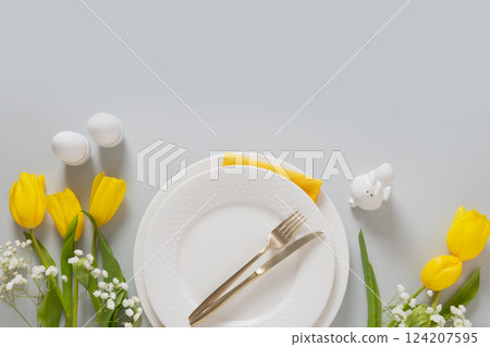 Easter frame with pastel yellow eggs, yellow tulips, gypsophila on gray background. View from above. Happy Easter greeting card. Easter frame with pastel yellow eggs, yellow tulips, gypsophila on gray background. View from above. Happy Easter greeting card. 124207595