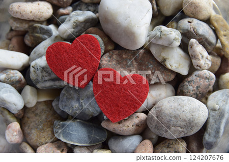 Red bright fabric hearts on the stones near the river. Natural and romantic background. 124207676