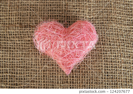 Heart shape made of pink material fabric on a rustic natural background with copyspace. Concept of Valentine's day and romantic love. 124207677
