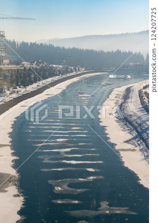 Winter serenity unfolds along a tranquil river surrounded by misty mountains and frosted trees in a peaceful landscape Winter serenity unfolds along a tranquil river surrounded by misty mountains and frosted trees in a peaceful landscape 124207725