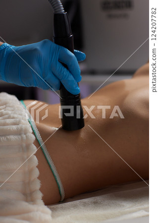 procedure removing cellulite on female abdomen, cavitation belly massage. Ultrasonic massage for weight loss. Correction of female figure without surgical intervention. Closeup of the tummy 124207782