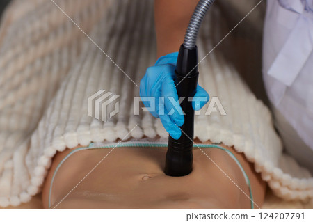 procedure removing cellulite on female abdomen, cavitation belly massage. Ultrasonic massage for weight loss. Correction of female figure without surgical intervention. Closeup of the tummy procedure removing cellulite on female abdomen, cavitation belly massage. Ultrasonic massage for weight loss. Correction of female figure without surgical intervention. Closeup of the tummy 124207791