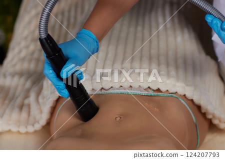 procedure removing cellulite on female abdomen, cavitation belly massage. Ultrasonic massage for weight loss. Correction of female figure without surgical intervention. Closeup of the tummy procedure removing cellulite on female abdomen, cavitation belly massage. Ultrasonic massage for weight loss. Correction of female figure without surgical intervention. Closeup of the tummy 124207793