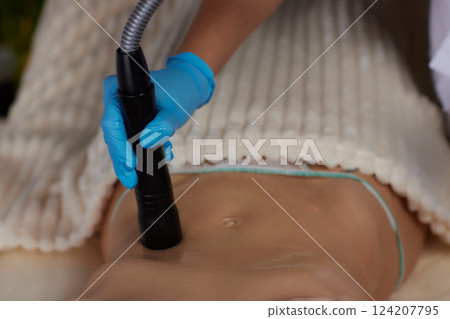 procedure removing cellulite on female abdomen, cavitation belly massage. Ultrasonic massage for weight loss. Correction of female figure without surgical intervention. Closeup of the tummy procedure removing cellulite on female abdomen, cavitation belly massage. Ultrasonic massage for weight loss. Correction of female figure without surgical intervention. Closeup of the tummy 124207795