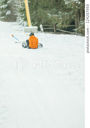 Winter wonderland adventure with snowboarder enjoying a thrilling descent on fresh snow amidst tall evergreen trees in a serene mountain landscape 124207950