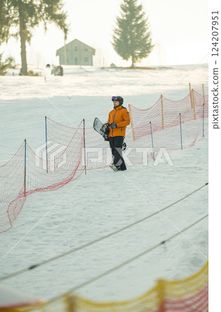 On a bright, clear winter day, a snowboarder eagerly gets ready for an exhilarating descent down the slopes, surrounded by a breathtaking landscape of sparkling snow and towering trees On a bright, clear winter day, a snowboarder eagerly gets ready for an exhilarating descent down the slopes, surrounded by a breathtaking landscape of sparkling snow and towering trees 124207951
