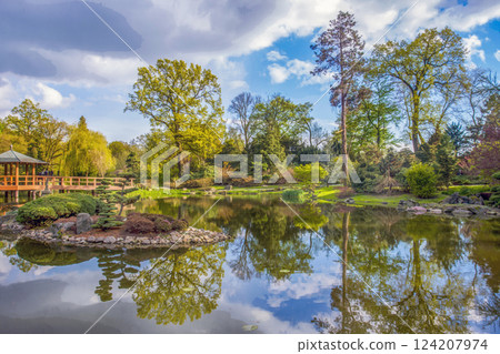 Amazing view of the Japanese garden in Wroclaw with a pond, wooden bridge with a gazebo, a topiary pine tree 124207974