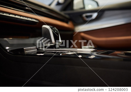Selector automatic transmission with leather in the interior of a modern expensive car. The background is blurred. Black and brown leather car. Selector automatic transmission with leather in the interior of a modern expensive car. The background is blurred. Black and brown leather car. 124208003