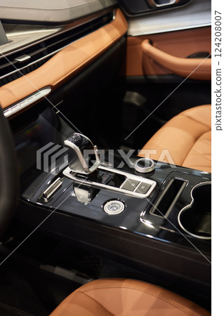 Selector automatic transmission with leather in the interior of a modern expensive car. The background is blurred. Black and brown leather car. Selector automatic transmission with leather in the interior of a modern expensive car. The background is blurred. Black and brown leather car. 124208007