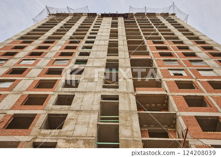 It is view of a new incomplete house without tiles on roof in sunny summer day. It is a close up view of modern house without roof. It is close up view of unfinished building apartment 124208039