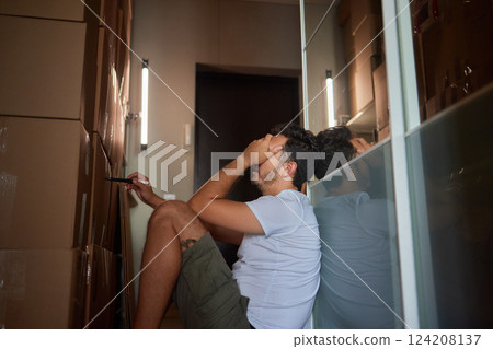 Man standing in living room on day of move to rented home, unbox carton box with belongings. Relocate to new own apartment collect personal things Man standing in living room on day of move to rented home, unbox carton box with belongings. Relocate to new own apartment collect personal things 124208137