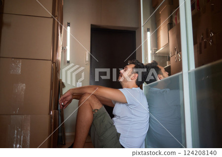 Man standing in living room on day of move to rented home, unbox carton box with belongings. Relocate to new own apartment collect personal things Man standing in living room on day of move to rented home, unbox carton box with belongings. Relocate to new own apartment collect personal things 124208140