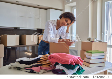 people, moving new place and repair concept - happy african american young woman with many cardboard boxes sitting on floor at home 124208305