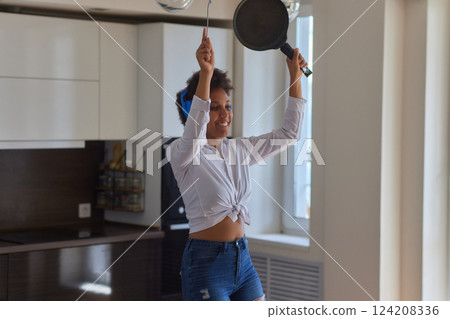 Overjoyed millennial girl wearing headphones have fun moving listening to music relax in living room, happy young woman in earphones dance enjoy leisure weekend at home, stress free concept 124208336