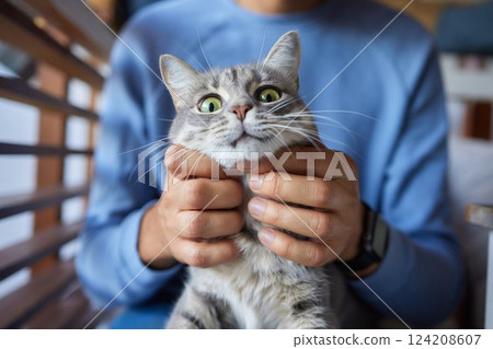 young man holding and petting cute cat male 124208607