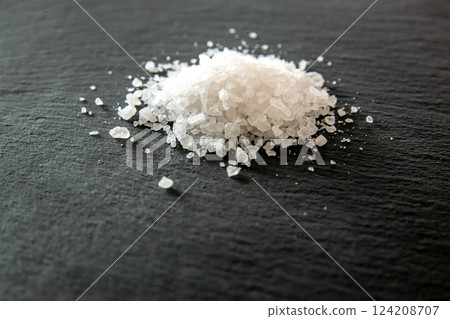 Salt crystals for cooking the food. Pile of sea salt on a black natural background.  124208707