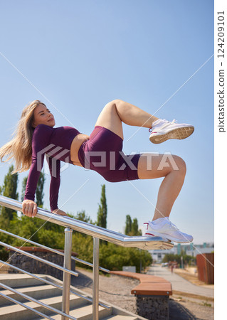 Portrait of fit and sporty young woman doing stretching in city. 124209101