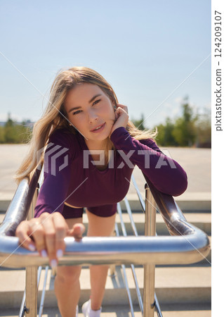 Portrait of fit and sporty young woman doing stretching in city. 124209107