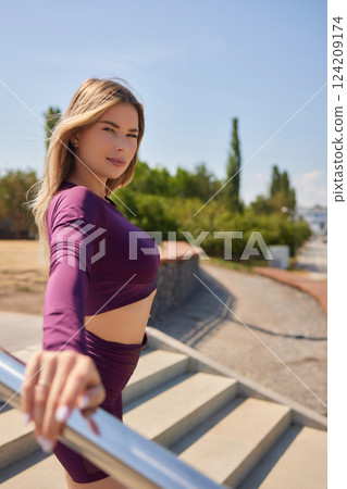 Portrait of fit and sporty young woman doing stretching in city. 124209174