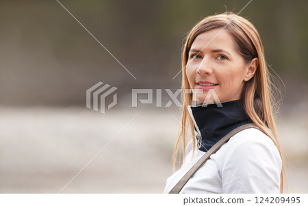 Portrait of young woman in white sport jacket, blurred horizon (river shore) in background, space for text left side 124209495