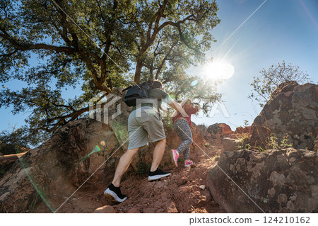 Father and daughter hiking on rocky trail under bright sunlight 124210162
