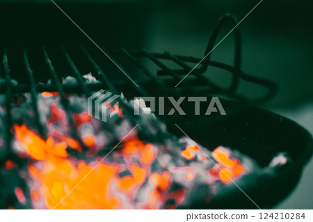 Smoldering wood on a metal barbecue grill. BBQ outdoors. Dangerous hot orange firewood. Fiery blaze. Cooking food on hot coals outside in nature. Smoldering wood on a metal barbecue grill. BBQ outdoors. Dangerous hot orange firewood. Fiery blaze. Cooking food on hot coals outside in nature. 124210284