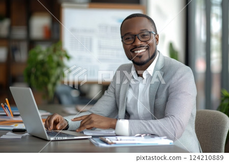 Professional man working on laptop in modern office smiling and engaged casual environment positive mindset for productivity 124210889