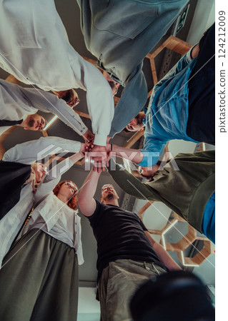 A group of young businessmen offer their hands together, symbolizing togetherness in the business world A group of young businessmen offer their hands together, symbolizing togetherness in the business world 124212009