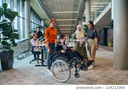 A diverse group of business colleagues is having fun with their wheelchair-using colleague, demonstrating their attention and inclusivity in the workplace 124212063